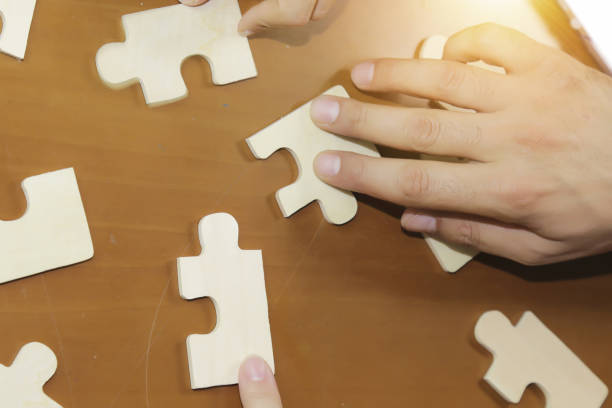 istock Business partnership or teamwork concept with a business people presenting a matching puzzle piece as they cooperate on finding an answer and solution, close up of their hands. 840699884