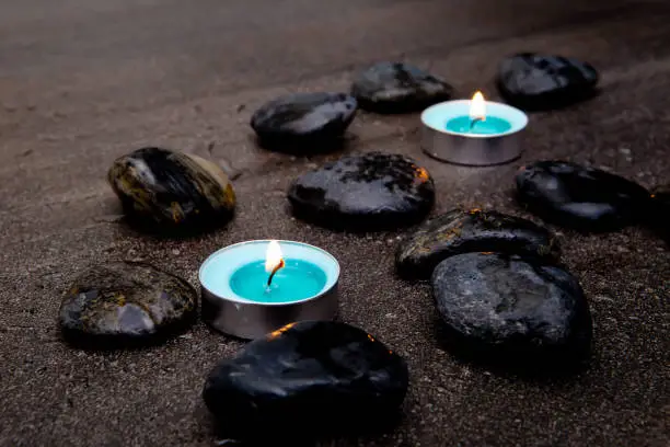 Photo of Turquoise candles with black rocks on gray slate background with water droplets