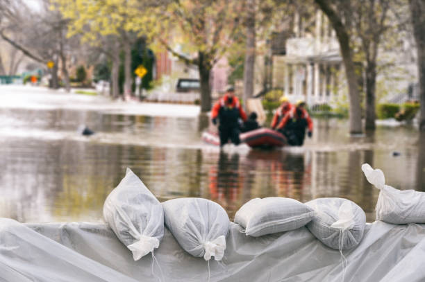 sacos de areia de proteção de inundação com casas inundadas no fundo (montagem) - condições meteorológicas extremas - fotografias e filmes do acervo