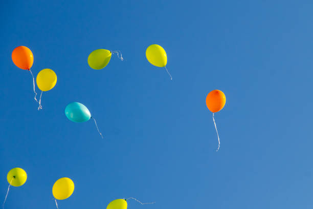 istock Colorful balloons flying in blue sky 840729366