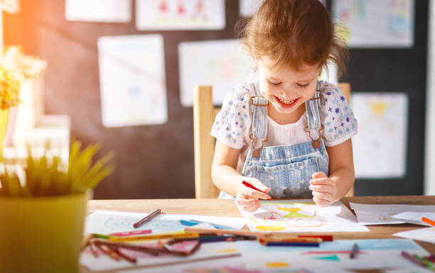 child  girl draws with colored pencils