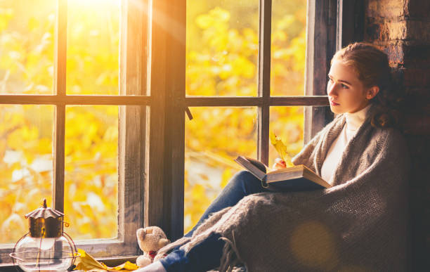 istock Happy woman reading book by autumn window 840733622