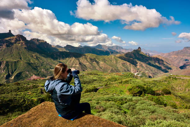 side view of hiker woman admiting the amazing landscapes with binocular.