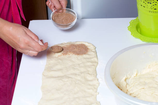istock A woman is cooking buns with cinnamon. She rolls the stuffing onto the rolled dough. Mixed sugar and cinnamon. 840750188