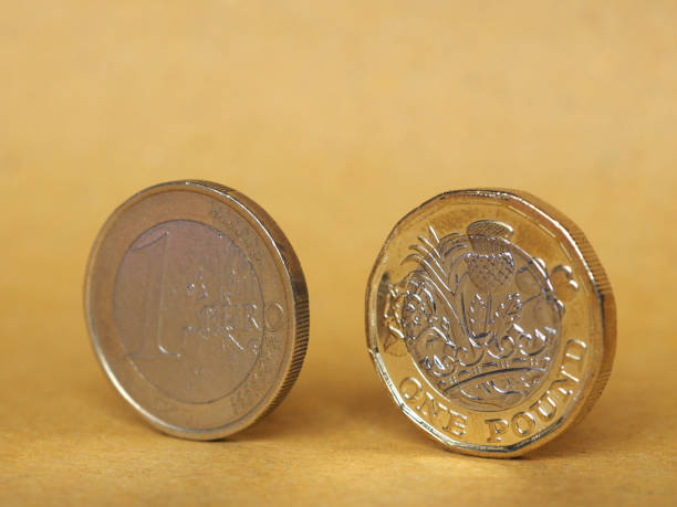 istock 1 pound and 1 euro coin over paper background 840766216