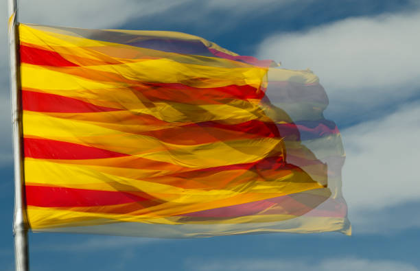 Catalan flag A double exposure shot of a large sunlit Catalan flag against a blue sky catalonia stock pictures, royalty-free photos & images