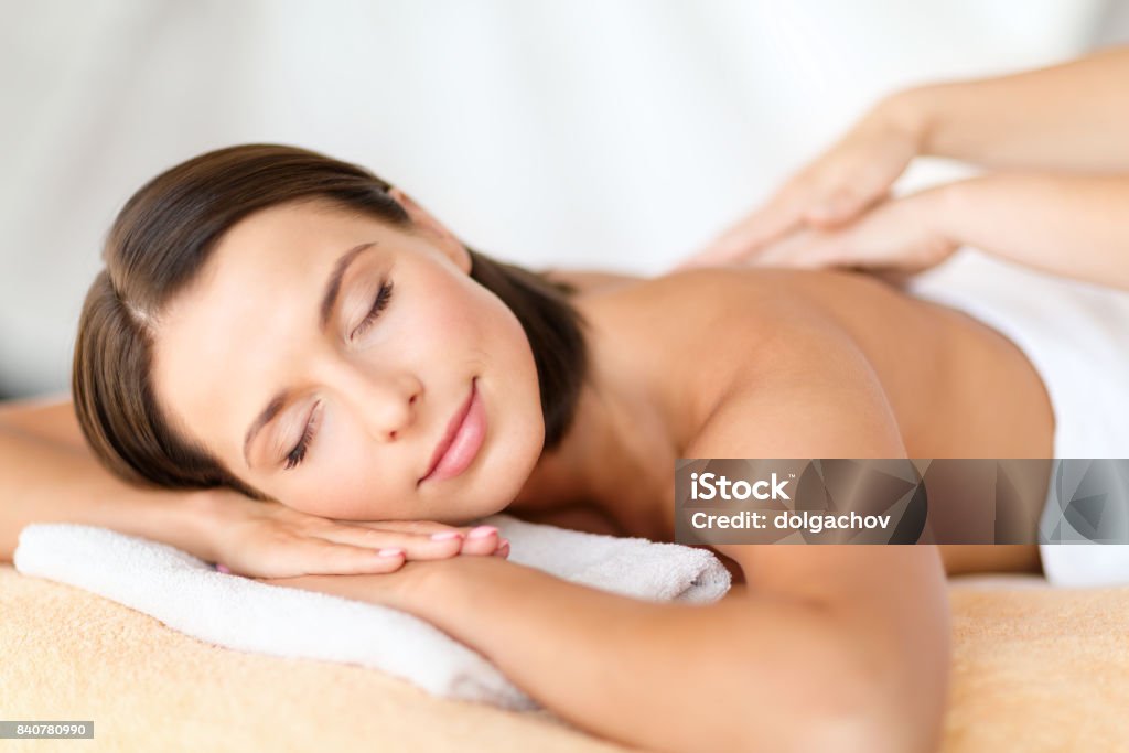 beautiful woman in spa salon getting massage health, beauty, resort and relaxation concept - beautiful woman with closed eyes in spa salon getting massage Massaging Stock Photo