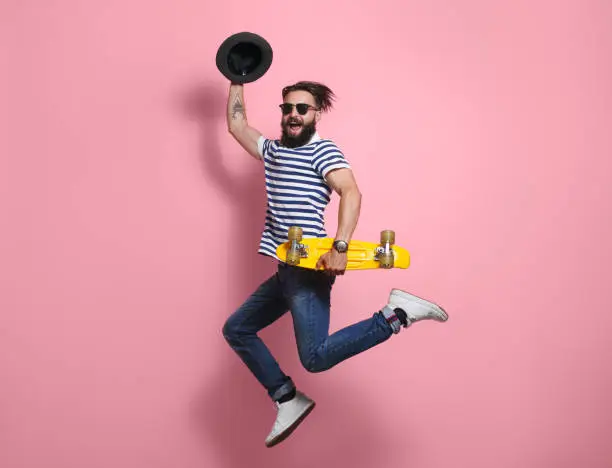 Photo of Hipster man jumping with longboard