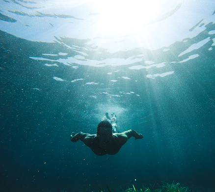 Low angle shot of a man swimming under the sea.
