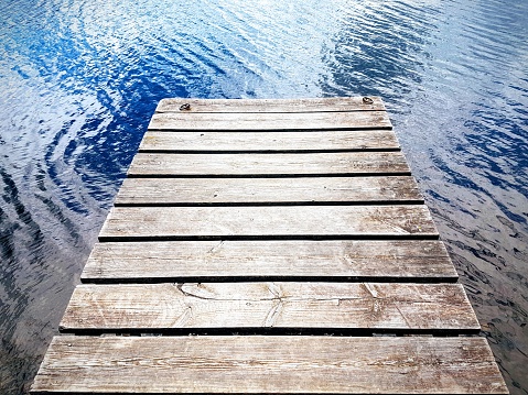 An old fashioned wooden pier over the water of a lake.