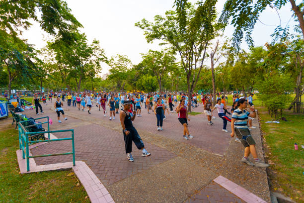 Thai people performing group aerobics exercise in Lumpini Park, part of health initiative in the capitol