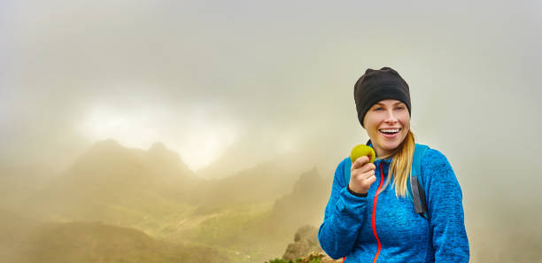 hiker woman eating an apple smiling hiker woman taking care of herself and eating an apple. teno mountains photos stock pictures, royalty-free photos & images
