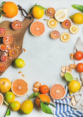 Natural fresh citrus fruits on wooden rustic board over grey marble table background, top view, copy space