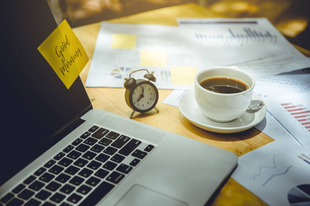 istock computer notebook, clock, cup of coffee and graphs papers put on wooden table. there is post it paper and wording 