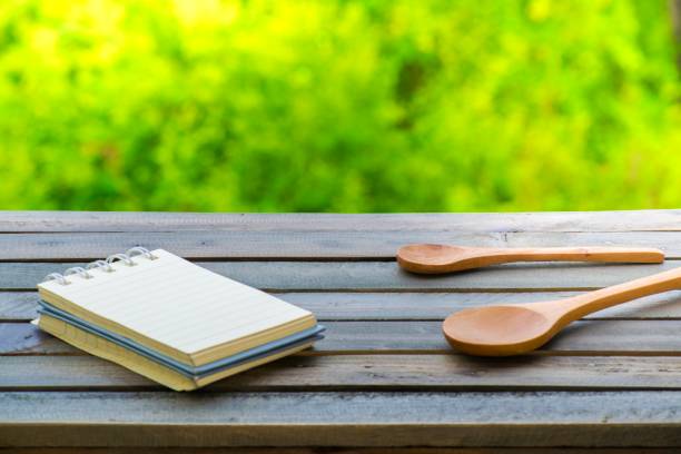 istock Notepad with spoons on wood tree blurry bokeh background.Using wallpaper for food, kitchen and cook composition image Take note product for book with paper and concept or copy space and note 840807104