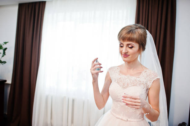 portrait d’une jeune mariée valable parfums sur son corps dans sa chambre un jour de mariage. - perfume wedding bride spraying photos et images de collection