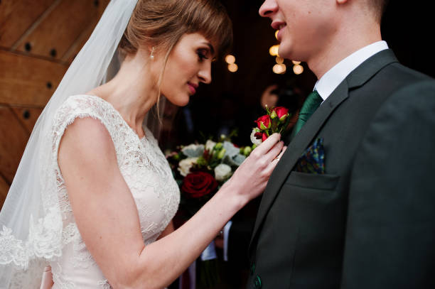 istock Beautiful bride pinning a buttonhole flower up to a groom's jacket. 840813432