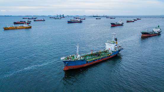 Aerial view Crude oil tanker under cargo operations on typical shore station with clearly visible mechanical loading arms and pipeline infrastructure.