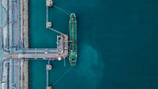 Aerial view Crude oil tanker Aerial view Crude oil tanker under cargo operations on typical shore station with clearly visible mechanical loading arms and pipeline infrastructure. harbor photos stock pictures, royalty-free photos & images
