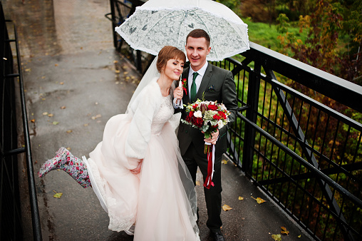 Wedding couple taking a walk with an umbrella on a rainy day.