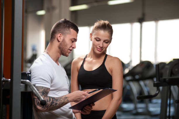 istock Personal trainer and his female client in gym 840814386