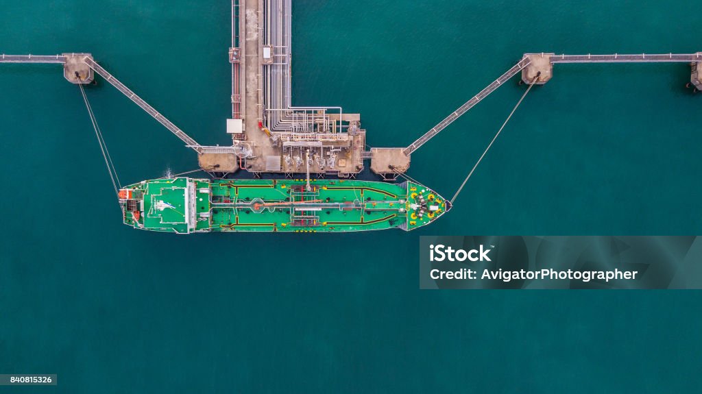 Aerial view Crude oil tanker Aerial view Crude oil tanker under cargo operations on typical shore station with clearly visible mechanical loading arms and pipeline infrastructure. Liquefied Natural Gas Stock Photo