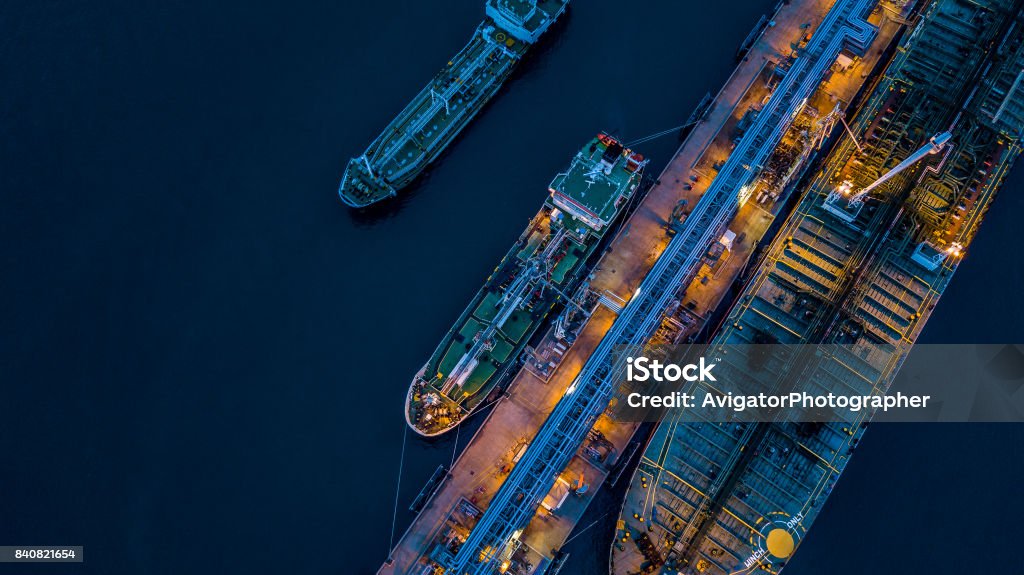 Aerial view Crude oil tanker Aerial view Crude oil tanker under cargo operations on typical shore station with clearly visible mechanical loading arms and pipeline infrastructure. Ship Stock Photo