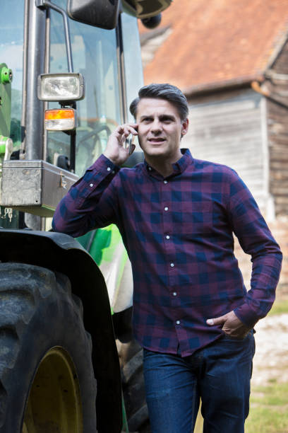 istock Farmer Next To Tractor Talking On Mobile Phone 840838430