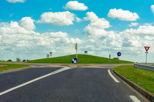 Empty French Roundabout on small hill with clean cut grass and impressive cloudscape