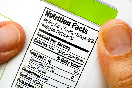 Woman fingers with protein jar. Reading nutrition facts.  Close-up.
