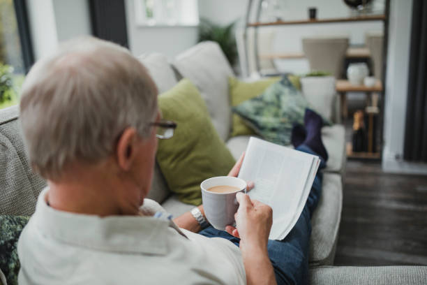 シニア新聞を読む - senior adult relaxation sofa reading ストックフォトと画像