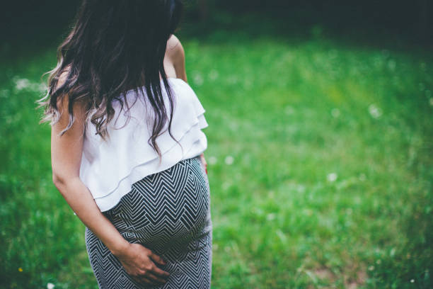 istock Pregnant woman standing on green grass 840861436