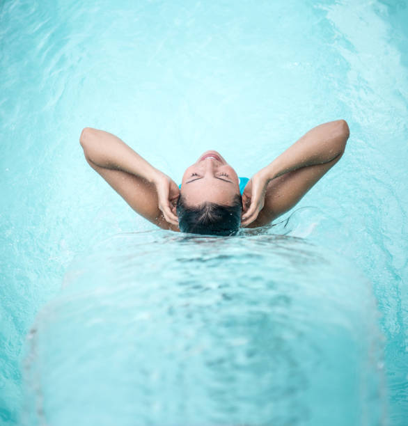 Peaceful woman relaxing under a waterfall at the spa