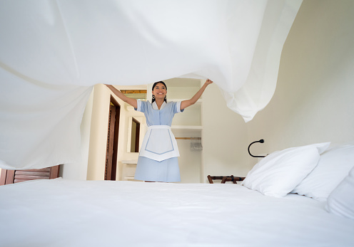 Latin American maid working at a hotel making the bed â people at work concepts