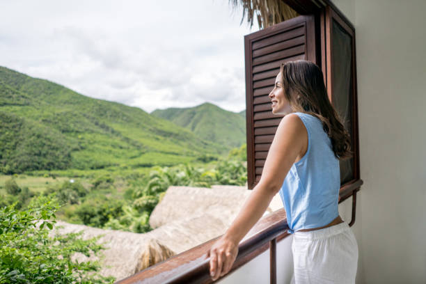 Woman traveling and enjoying the view from her hotel Portrait of a beautiful woman traveling and enjoying the view from her hotel room country inn stock pictures, royalty-free photos & images