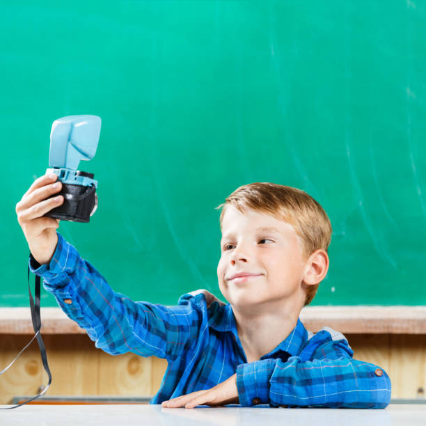 istock Schoolboy make selfie at blackboard in school 840866124