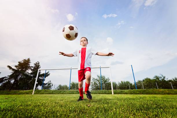 istock Boy playing with football ball on playing field. 840867076