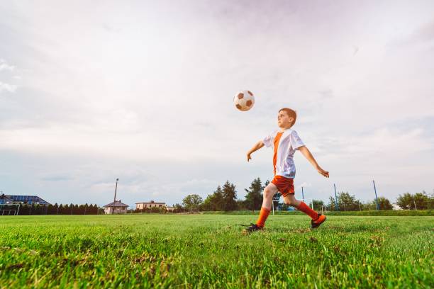 istock Boy playing with football ball on playing field. 840867254