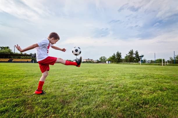 istock Boy playing with football ball on playing field. 840869382
