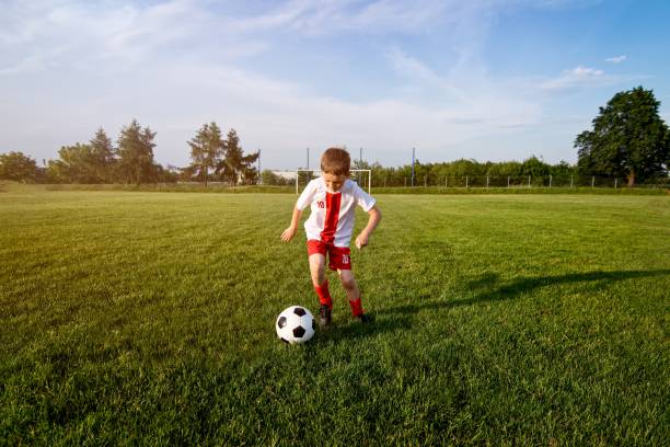 istock Boy playing with football ball on playing field. 840869538
