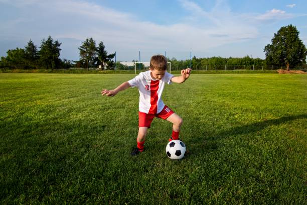istock Boy playing with football ball on playing field. 840869788