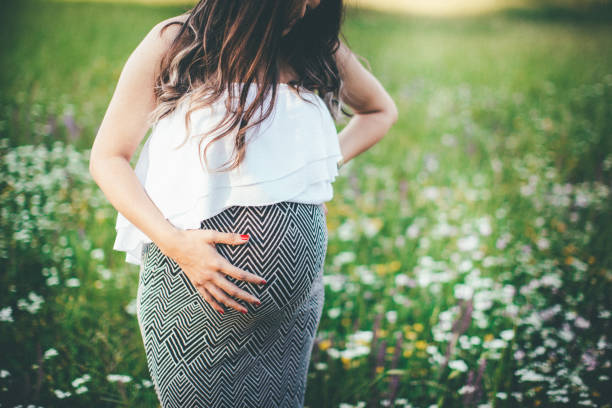 istock Pregnant woman standing on green grass 840873888