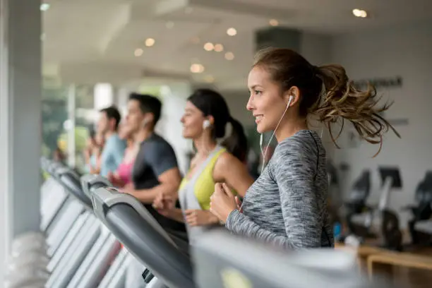 Portrait of a beautiful woman exercising at the gym running on a treadmill - fitness concepts