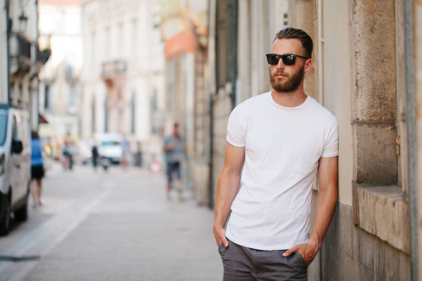 Hipster handsome male model with beard wearing white blank t-shirt with space for your logo or design in casual urban style