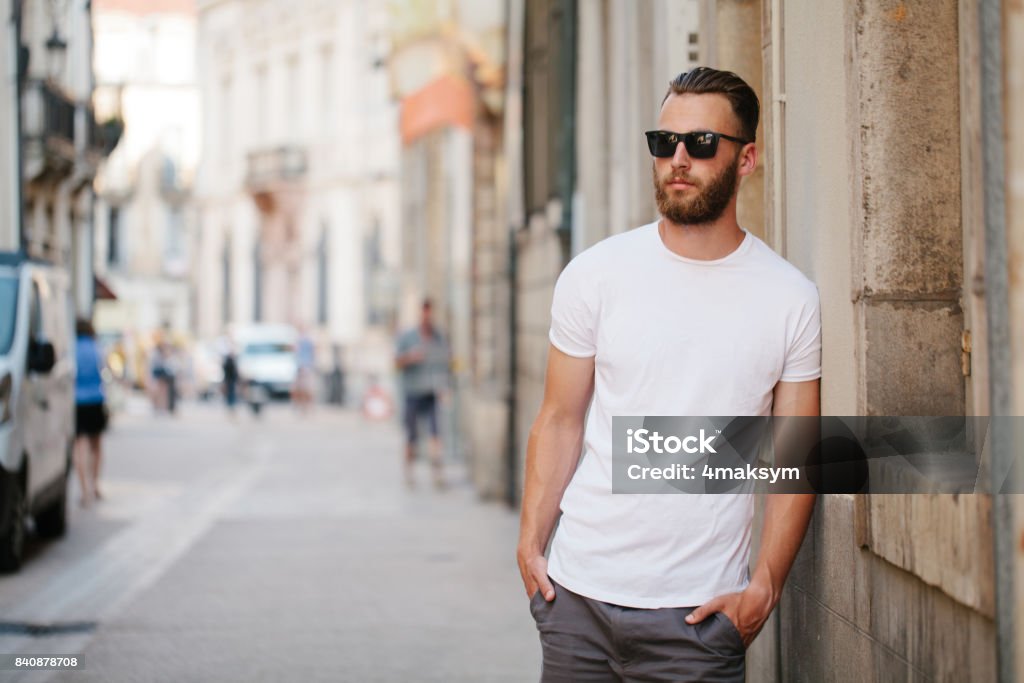 Hipster handsome male model with beard wearing white blank t-shirt with space for your logo or design in casual urban style T-Shirt Stock Photo