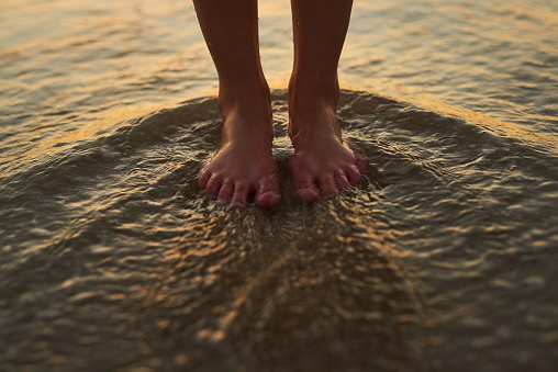 Cropped shot of a woman standing with her feet in the water