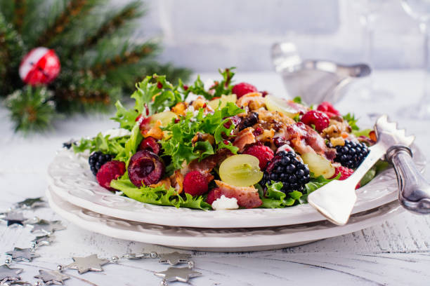 Delicious colorful salad for Christmas dinner Colorful salad with fruits, berries, chicken breast, bacon and nuts. Delicious Christmas themed dinner table. Copy space appetizer plate stock pictures, royalty-free photos & images
