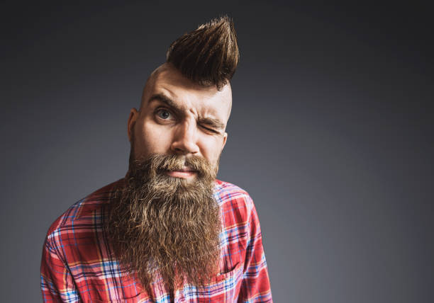 Young trendy punk man portrait Young punk rocker man looking at camera. Isolated on gray background mohawk stock pictures, royalty-free photos & images