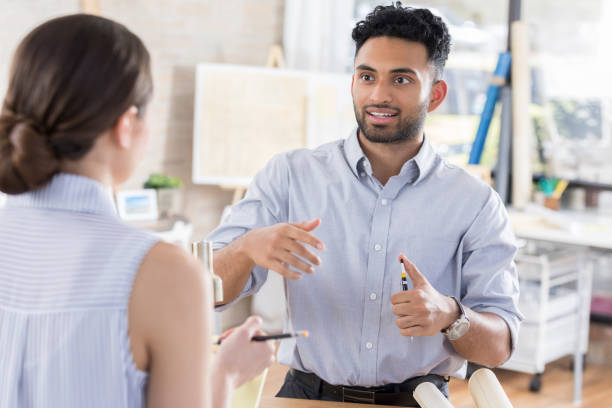 istock Animated young architect discusses plans with coworker 840890210