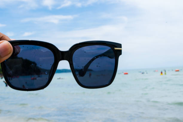 istock hand holding sunglasses on the beach 840891602